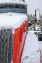 Red classic bonnet big rig semi truck tractor standing on the winter parking lot covered with snow and ice Royalty Free Stock Photo