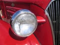 Red classic car headlight and partial grill Royalty Free Stock Photo