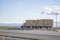 Red classic powerful big rig semi truck transporting pressed hay on two flat bed semi trailer driving on the straight highway road Royalty Free Stock Photo