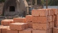 Red clay bricks stacked outdoors with industrial kiln in soft natural light Royalty Free Stock Photo
