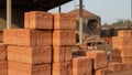 Red clay bricks stacked outdoors with industrial kiln in soft natural light Royalty Free Stock Photo