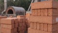 Red clay bricks stacked outdoors with industrial kiln in soft natural light Royalty Free Stock Photo