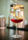 Red clear drink in vintage champagne glass with orange zest decoration on a bar table Royalty Free Stock Photo