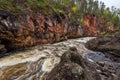 Red cliff, stone wall, forest, waterfall and wild river view in autumn Royalty Free Stock Photo