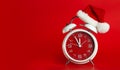 Red clock with Christmas Santa hat. Time for Christmas shopping concept. Blank red space for text Royalty Free Stock Photo