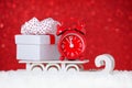 Red clock with a gift box over sleigh in snow on red background Royalty Free Stock Photo