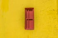 Red closed barred window in the yellow wall. Royalty Free Stock Photo