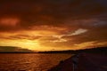 Fiery orange sunrise over river dam. Car on the road under clouds at dusk. Cloudscape in twilight. Bloody sky. Last day on Earth.