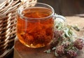 Red clover tea in glass cup on wood on rustic background of wicker, herbal drink is good for menopause, bone, heart health