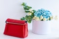 Red clutch bag for women on the background of a basket with flowers. Light white background Royalty Free Stock Photo