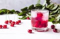 Red cocktail with cherry and ice on a white wooden background. Fresh summer cocktail with cherries and ice cubes Royalty Free Stock Photo