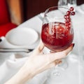 Red cocktail with cranberries, glass in hand
