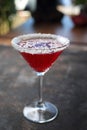 Red cocktail in martini glass with shredded coconut rim, selective focus. Red coconut and strawberry margarita.