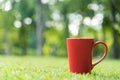 Red coffee cup on green grass field in morning time Royalty Free Stock Photo