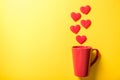 Red coffee cup with smoke heart on yellow paper background