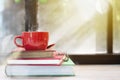 Red coffee cup with smoke on top of stacked old books on wood ta