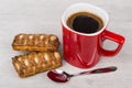 Red coffee cup, stuffed flaky cookies and spoon on table