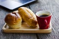 Red coffee cup and Tasty buns on wooden plate with latop computer on wood table backgrounds