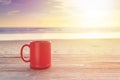 Red coffee cup on wood table at sunset or sunrise beach Royalty Free Stock Photo