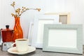 red coffee pot with cup and orange glass vase against empty photo frames Royalty Free Stock Photo