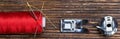 Red coil thread on a wooden background, with a set of spare parts for a sewing machine