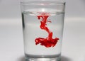 Red color drop on the water in the glass with white background.