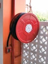 Red color fire hose reel mounted on concrete wall.