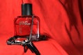 Red color men perfume bottle isolated on red background with female accessories. Perfume bottle of `Wild Stone` with black cap