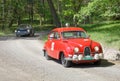 Red color Saab 96 classic car from 1964 driving on a country road