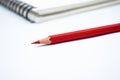 Red color wood pencil crayon placed in front of a white note paper diary Royalty Free Stock Photo