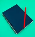 A red color wood pencil crayon placed on top of a blue colored paper diary Royalty Free Stock Photo