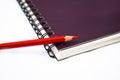 Red color wood pencil crayon placed on top of a purple color spiral note book Royalty Free Stock Photo
