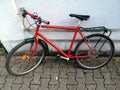 Red colored bicycle leaned on a white wall of a building with old brick flooring Royalty Free Stock Photo