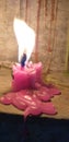 A red colored candle is glowing and melting its own wax.