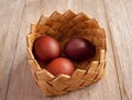 Red colored spring Easter eggs in a basket from bast on natural wooden background
