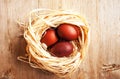 Red colored spring Easter eggs in a nest from sisal bast on natural wooden background
