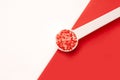 Red colored sugar in white spoon on red background - red crystals edble decor