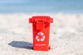 Red colored trash can recyclables with paper, plastic, glass and organic waste suitable for recycling on sandy beach. Segregate