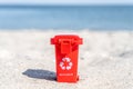 Red colored trash can recyclables with paper, plastic, glass and organic waste suitable for recycling on sandy beach. Segregate