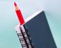 A red colored wood pencil crayon placed inside of a blue colored paper diary Royalty Free Stock Photo