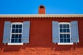 Red colorful facade of the old house with two windows with open wooden shutters Royalty Free Stock Photo