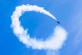 Red combat fighter with white circle smoke behind in the blue sky