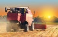 Red combine harvester soybean harvest against the backdrop of the sun in the sky. The farm operates in the field in the autumn sea Royalty Free Stock Photo