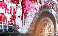 Red compact SUV car with sport and modern design washing with soap. Car covered with white foam. Car care service business concept Royalty Free Stock Photo