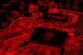 Red computer motherboard featuring a biohazard logo, concept of virus ransomware and spamware attack