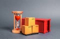 Red container with cardboard boxes and an hourglass. Express delivery in short time concept. Temporary storage, limited offer Royalty Free Stock Photo