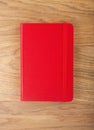 Red copybook with elastic band on wooden background. Royalty Free Stock Photo