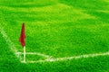 Red corner flag on a football field with bright fresh green turf grass and white soccer touch lines. Royalty Free Stock Photo