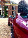 Red Corvette parked at a beautiful mansion