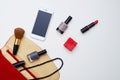 Red cosmetics case on white field, objects arranged in a semi-ch